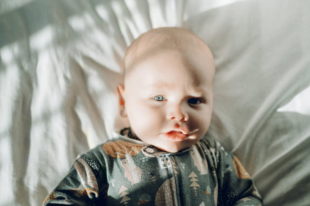 Baby, face and portrait with cute child in nursery, relax with growth and early childhood development. Sunshine, morning and little kid at family home, calm adorable infant in bed and aboveの写真素材