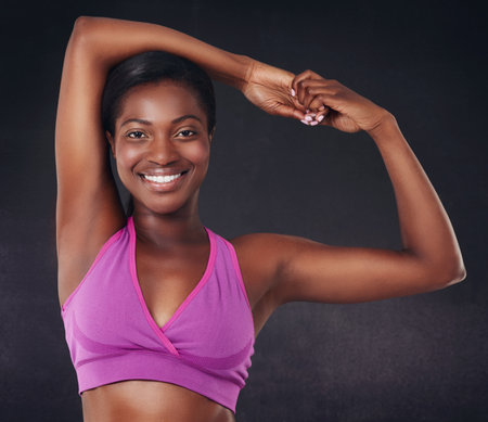 Stretching, health and portrait of black woman in studio for fitness, personal trainer and gym workout. Wellness, training and warm up with person from Ghana on dark background for exercise.の写真素材