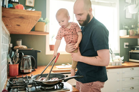 Cooking, kitchen and a man at home with his baby in the morning together for food or lunch preparation. Family, children or kids with a father and infant boy in a house to make a meal while bondingの写真素材