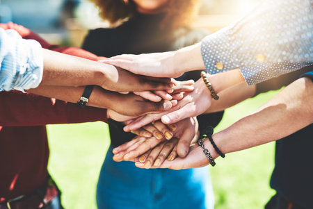 College students, closeup or hands together in huddle in outdoor campus meeting for group teamwork. People, lens flare or university friends in collaboration for learning or education study at schoolの写真素材