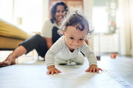 Mother, family and baby crawling on floor in living room learning to walk, child development and motherhood. Love, home and happy mom and kid for bonding, quality time and relax together on floorの写真素材