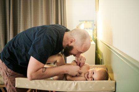 Father, diaper change and playing with a baby in the nursery of a home for hygiene a single parent. Family, kids and a man with his infant child, changing a nappy for cleaning or care in a houseの写真素材
