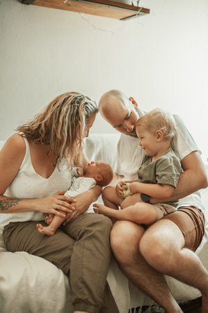 Dad, mom and baby with family on couch, sofa or quality time together in living room, home or house. Mother, father and parents to love, support or care for young children, kids and embracing babiesの写真素材
