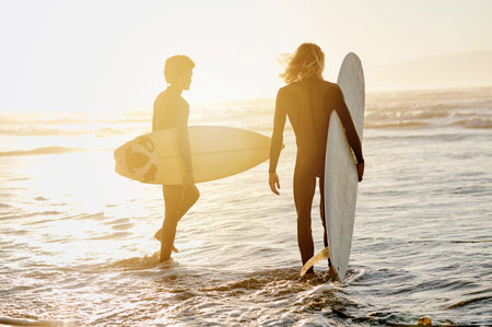 Back view, men and surfing friends at sunset beach for waves, freedom and swimming. Silhouette of...