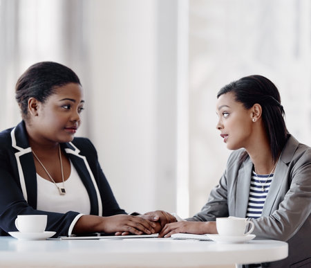 Listen, women and holding hands as empathy, care and support in office as psychologist for company. Female people, comfort and compassion for grief counselling, conversation and mental health at workの写真素材
