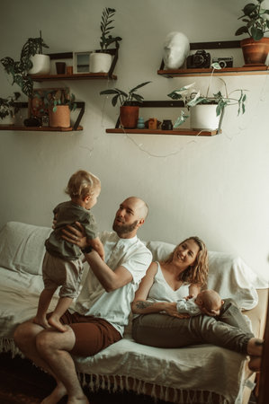 Family, playing and parents with baby and toddler on a sofa with smile, care and relax in their home together. Newborn, love and mother and father with children in a living room bonding in a houseの写真素材