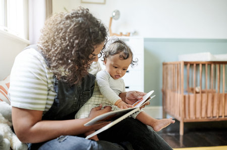 Family, child development or book with a mother and baby reading a book in a home bedroom together....