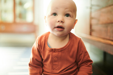 Looking, innocent and baby on the living room floor for playing, explore and curious in a house. Young, beautiful and a toddler sitting in the lounge for play, relaxation and adorable at homeの写真素材