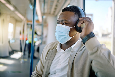 Black man, headphone and face mask for train travel with compliance, health safety and morning...