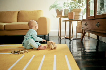 Baby, toy car and play in home, having fun and learning, relaxing or growth. Development, childhood and kid, newborn or toddler playing with wooden truck or toys and enjoying time alone in house.の写真素材