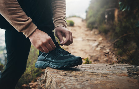 Trekking, shoes and tying laces with person in nature for explore, health and adventure. Challenge, wellness and holiday with closeup hiking on path for walking, fitness and camping vacationの写真素材