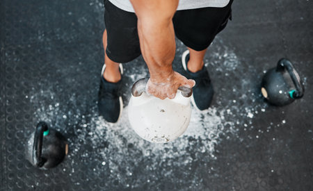 Above Bodybuilder, hands and chalk for kettlebell, exercise or workout for arm strength at gym. Man, weights and sports athlete for weightlifting, muscle power and health club fitness performanceの写真素材