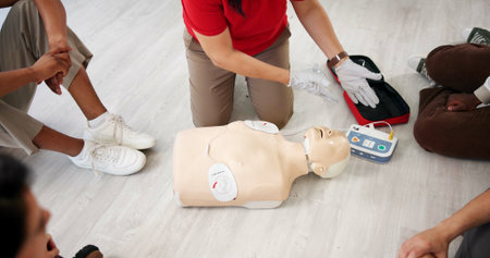 Mannequin, teaching and workshop with people and defibrillator for first aid, cardiac arrest or...