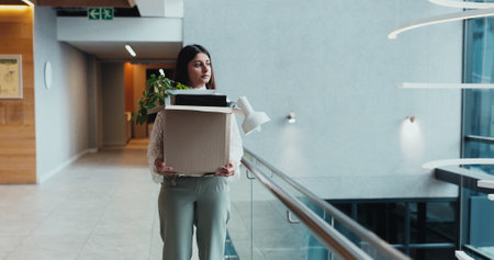 Sad, corporate and woman walk with box for work dismissal, fired and retrenched of unemployment. Unhappy, female person and items for resignation, termination eviction and recession notice of joblessの写真素材
