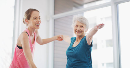 Yoga, senior woman and happy coach for fitness, healthy body or warrior pose for geriatric wellness. Stretching, pilates trainer and exercise together for physical therapy, help and laughing in gymの写真素材