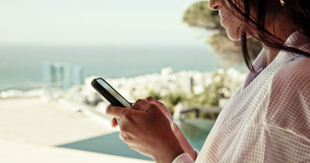 Woman, hands and phone at hotel for travel, social media update or accommodation review. Influencer, summer vacation and mobile on resort rooftop for booking app, follower interaction or hospitalityの写真素材
