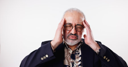 Headache, glasses and senior man in studio, stress and overworked on white background. Pensioner, mature person and model with eyewear, migraine and frustrated with anxiety, pressure and confusedの写真素材