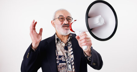 Senior man, speech and megaphone in studio with announcement, broadcast and retirement justice. Speaker, microphone and noise for change of law, society support and call to action on white backgroundの写真素材