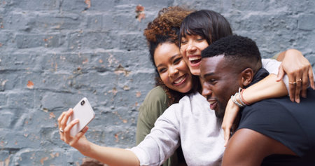 Selfie, laughing and group of people by wall in city for memory, social media or profile picture on...