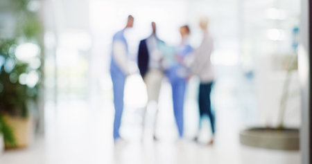 Blur, doctors and people in hospital, lobby and with medical insurance, teamwork and conversation. Group, employees and professional in hallway, healthcare and decision with choice and cooperationの写真素材
