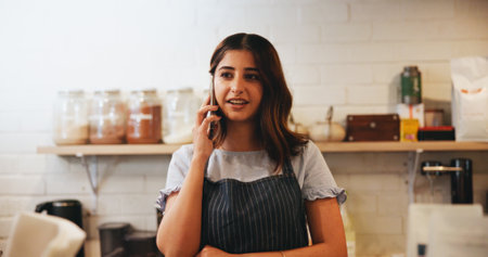 Cafe, barista and business owner with phone call for restaurant management, orders or customer service. Entrepreneur, waiter and woman with digital technology for coffee shop, startup or ecommerceの写真素材