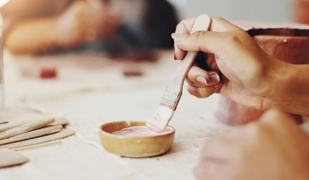 Hands, brush and pottery in clay studio, workshop and art process for handmade ceramic design....