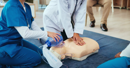 Mask, hands or nurses learning cpr on mannequin for first aid, cardiac arrest or healthcare protocol. Medical class, students or people with respiratory tool in paramedic course or nursing schoolの写真素材