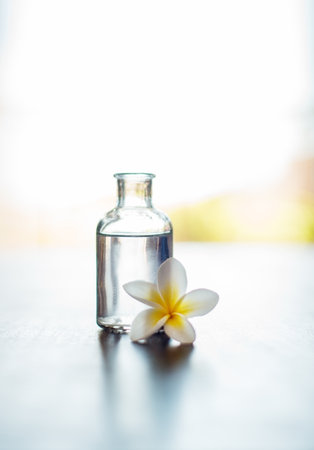 Wellness, mockup and essential oil with flower on table for skin health, healthy body and aromatherapy massage. Interior space, cosmetics and healing product for skincare, antioxidants and anti agingの写真素材
