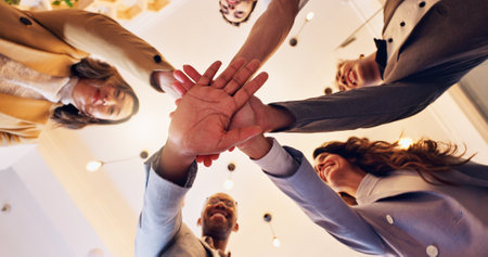 Happy, business people and meeting with hands together below for unity, motivation or teamwork at office. Low angle, group or employees piling with smile or trust for mission, synergy or solidarityの写真素材