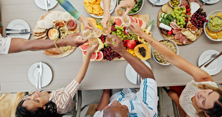 Above, hands and people cheers with champagne for birthday party, social gathering and celebration. Friends, toast and alcohol with healthy food, holiday event and group reunion for bonding togetherの写真素材