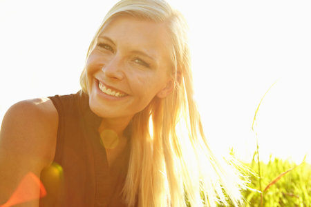 Relax, travel and woman in nature for summer with self discovery, freedom or peaceful holiday. Smile, lens flare and female person in field of grass for calm, mindfulness or personal growth.の写真素材
