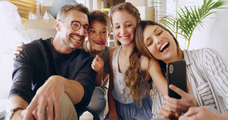 Home, father and mother with children for selfie, family memory and profile picture for social media. Parents, girl and boy with tongue out for photography, happiness and bonding together in houseの写真素材