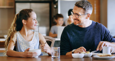 Dad, girl and breakfast with conversation in home, happy or eating with nutrition, bonding and care. People, father and daughter with food, smile and talk with memory, love and listen in family houseの写真素材