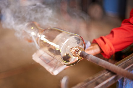 Cloth, glass and smoke with hands of artisan person in forge or foundry for manufacturing process. Bottle, cleaning and heat with professional glassblower in factory, plant or workshop for productionの写真素材
