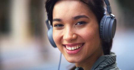 Headphones, happy and portrait of woman in city with music for commuting to university in morning. Travel, audio tech and female student listening to online playlist, podcast or radio in urban town.の写真素材