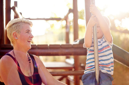 Happy, playground slide and mom with child in park for playing, childhood and adventure outdoors....