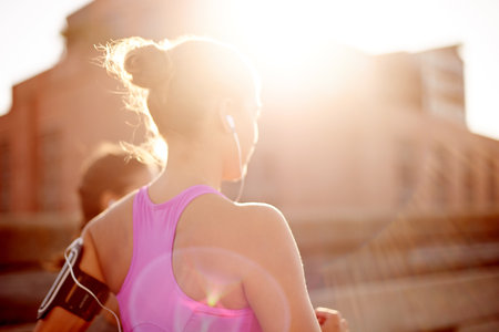 Fitness, music and running with sports woman outdoor on bridge in city for cardio challenge. Competition, exercise and training with athlete people in urban town together or marathon or raceの写真素材