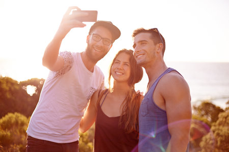 Friends, group selfie and sunset walk on mountain for countryside, travel or adventure to explore nature. Vacation, people and memories with natural environment for hiker, hobby or bonding togetherの写真素材