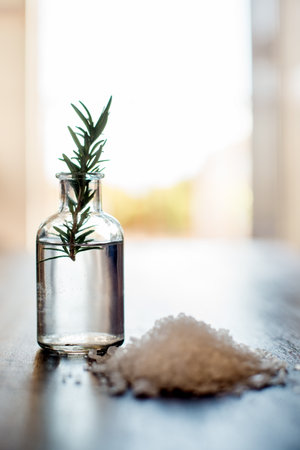 Spa, body care and rosemary essential oil with salt on table for aromatherapy treatment, wellness or swedish massage. Interior space, health clinic and empty room with natural products for selfcareの写真素材