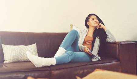 Tablet, student and thinking with woman on sofa for college application, University portal and reflection. Vision, idea and academy admission with African person in living room at home for updateの写真素材