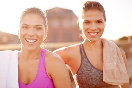 Fitness, sisters and portrait of happy women outdoor for exercise, training and athlete on workout break at sunset. Sports, twins and together in city for body health, wellness and relax with familyの写真素材