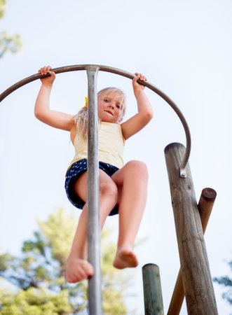 Playground, portrait and girl with fun, activity and energy with break, games and happiness. Below, kid and jungle gym with summer holiday, carefree and motivation with child development and growthの写真素材