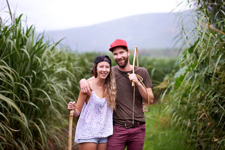 Happy couple, portrait and hiking outdoor with stick for travel, adventure or embrace for love in countryside. Man, woman and trekking in nature together for tourism, vacation or journey in Australiaの写真素材