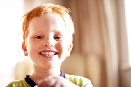 Boy, portrait and smile with kid in home for child development, growth or playful expression. Adorable, cute or growing up and happy youth with red hair in apartment for innocence or childhoodの写真素材