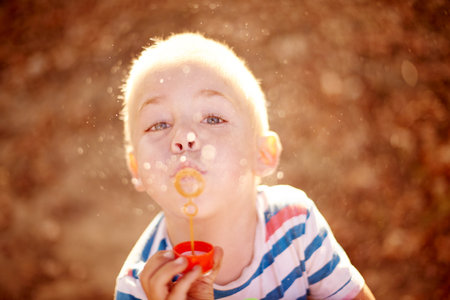 Bubbles, portrait and child in park with fun, sunset adventure and outdoor development for kids in nature. Relax, weekend and boy in garden playground with soap wand, childhood games or play activityの写真素材