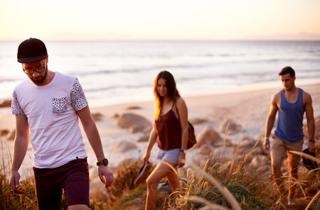 Walking, travel and people by beach for journey, weekend trip or adventure on seaside vacation. Discovery, fun and group of friends by ocean for holiday or getaway in nature together for bonding.の写真素材