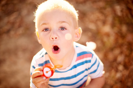 Hes adora-bubble. Shot of a cute little boy blowing bubbles in the outdoors.の写真素材