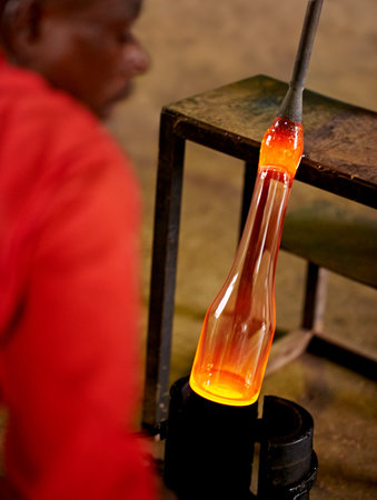 Glassblower, tools and black man in warehouse, productivity and skills with craftsmanship, industry and process. African person, technique and employee in workshop, manufacturing and equipmentの写真素材