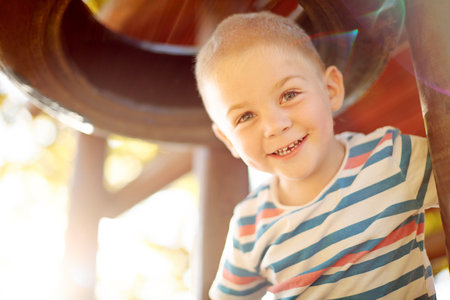 Development, growth and portrait of boy at playground, having fun in nature for activity, games or play. Coordination, motor skills and smile of happy child outdoor at jungle gym in park with flareの写真素材