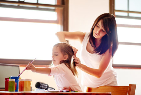 Painting, mother and art with girl in house for child development, helping and education. Creative, kindergarten and sketch with kid and mom brushing hair in family home for future, youth and colorの写真素材